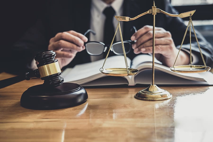 Lawyer holding glasses reading a book at a desk in his office